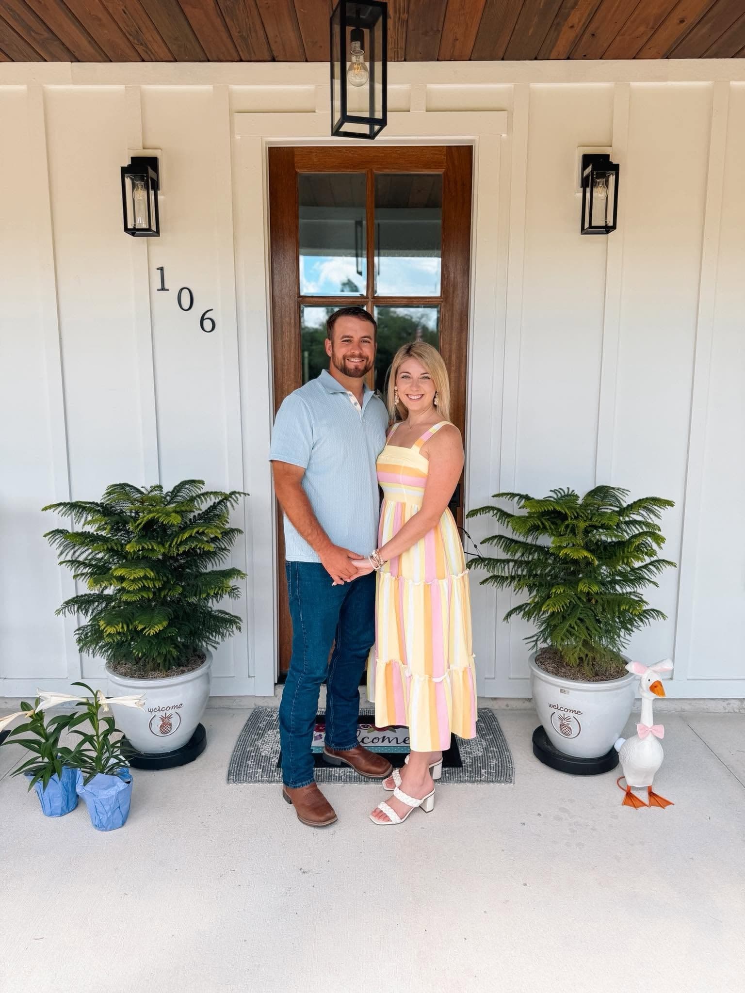 Robert and Taylor Johnson standing together on the front porch of a completed custom home